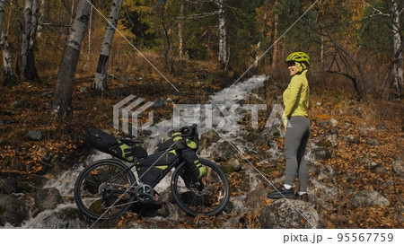 The woman travel on mixed terrain cycle touring with bikepacking. The traveler journey with bicycle bags. Sport tourism bikepacking. The woman travel on mixed terrain cycle touring with bikepacking. The traveler journey with bicycle bags. Sport tourism bikepacking. 95567759