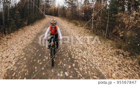 One caucasian children rides bike road in autumn park. Little girl riding black orange cycle in forest. Kid goes do bicycle sports. Biker motion ride with backpack and helmet. Mountain bike hard tail. One caucasian children rides bike road in autumn park. Little girl riding black orange cycle in forest. Kid goes do bicycle sports. Biker motion ride with backpack and helmet. Mountain bike hard tail. 95567847