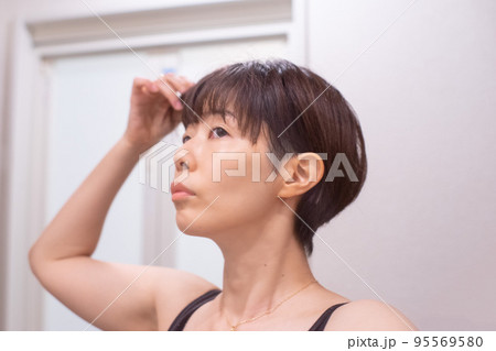 鏡の前で髪の毛を気にしている女性 鏡の前で髪の毛を気にしている女性 95569580