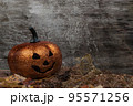 Glittering pumpkin in autumn leaves on wooden desk. Halloween background 95571256