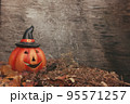 Funny pumpkin in autumn leaves on wooden desk. Halloween background 95571257