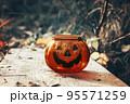 Halloween pumpkin candlestick in autumn forest. Laughing Candlelight 95571259