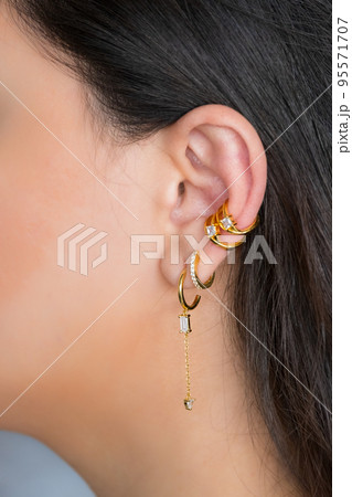 Woman ear with mulriple piercings wearing beautiful earrings with zirconia.  Beautiful valentine's gift. 95571707