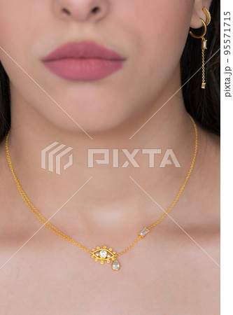 Young woman wearing a golden necklace and golden earrings. Beautiful valentine's gift. Young woman wearing a golden necklace and golden earrings. Beautiful valentine's gift. 95571715