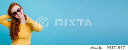 Portrait of happy ginger red hair girl with freckles smiling looking at camera. Pastel blue background. Copy Space 95571967