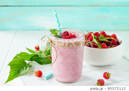 Raspberry milkshake or smoothie on a dark wooden table. Healthy juicy vitamin drink diet or vegan food concept. Copy space. 95572112