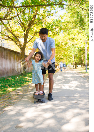 Portrait of Asian father and his daughter skateboarding in park 95572636
