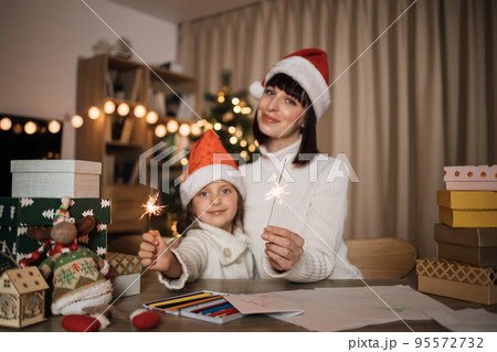 Focus on hands with sparkles, blur background of cheerful girl and her mother with charming smile 95572732