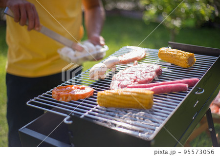 Close-up of steak, sausages and vegetables on BBQ 95573056