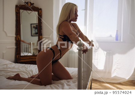 Extremely beautiful and young adult caucasian woman wearing lingerie in a boudoir bedroom setting in various poses. 95574024