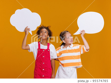Funny multinational girls with thought clouds on yellow background Funny multinational girls with thought clouds on yellow background 95574765
