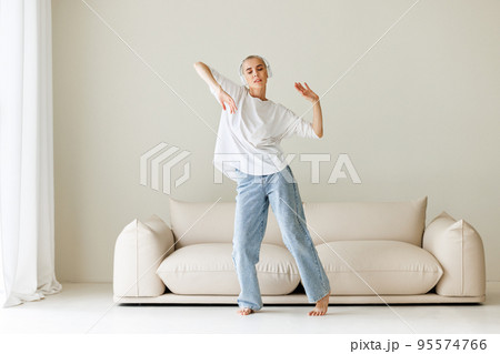 Beautiful woman meloman with very short hair dancing near couch 95574766
