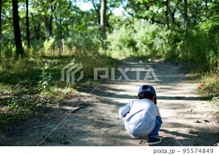 森林の散歩道の中で土が気になってしゃがんでいる男の子 森林の散歩道の中で土が気になってしゃがんでいる男の子 95574849