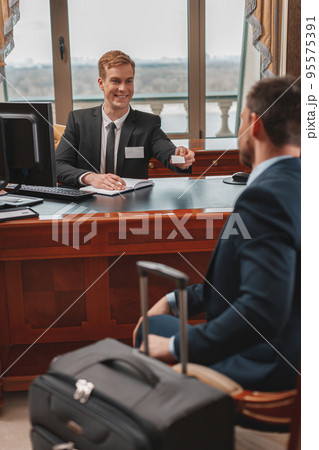 Businessman with bagguge is check in luxury hotel and receiving key card from receptionist Businessman with bagguge is check in luxury hotel and receiving key card from receptionist 95575391