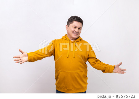Welcome, wide open hug. Middle aged man stretching hands to camera and smiling broadly, going to embrace, share love, wearing urban style hoodie. Indoor studio shot isolated on white background. Welcome, wide open hug. Middle aged man stretching hands to camera and smiling broadly, going to embrace, share love, wearing urban style hoodie. Indoor studio shot isolated on white background. 95575722