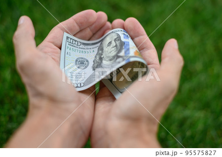 Close up 100 Dollar bank note in hand on grass background. One hundred American dollars. Close up 100 Dollar bank note in hand on grass background. One hundred American dollars. 95575827