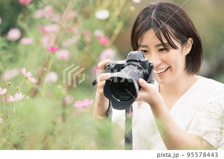 カメラでコスモスを撮る女性 95578443