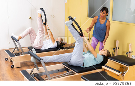 Teens doing pilates exercises with trainer 95579863