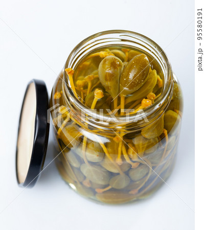 Pickled capers in glass jar on wooden table Pickled capers in glass jar on wooden table 95580191