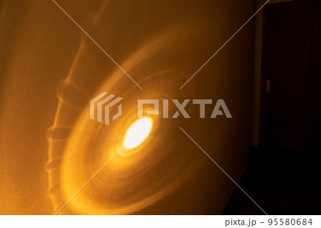 暗い廊下の壁を照らすオレンジ色の光 95580684