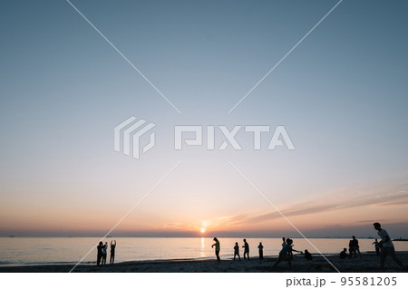 夕焼けの海で過ごす人たちのシルエット 95581205