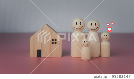 Happy house concept. Model house with wooden dolls standing lined up on pink background and heart icons. Indicates happiness and love in the home. 95582147