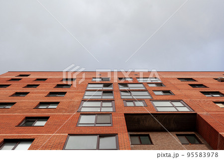 Brick high-rise new square house on a blue sky background. View from the courtyard to the top of the sky. Luxury housing and offices for work. Brick high-rise new square house on a blue sky background. View from the courtyard to the top of the sky. Luxury housing and offices for work. 95583978