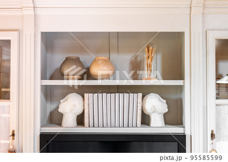 Head shaped bookends with books and clay pot on a shelf indoors. Interior design. Head shaped bookends with books and clay pot on a shelf indoors. Interior design. 95585599