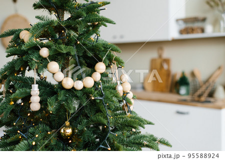 Stylish wooden beads on a Christmas tree in the dining room of a Scandinavian home Stylish wooden beads on a Christmas tree in the dining room of a Scandinavian home 95588924