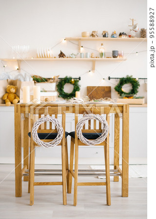 Wooden dining table with chairs decorated for Christmas and New Year in a bright Scandinavian style dining room 95588927