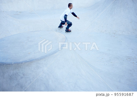 Mature male inline roller training in public skate park. Practicing jumps, tricks. Concept of active lifestyle, sport, hobbies. 95591687