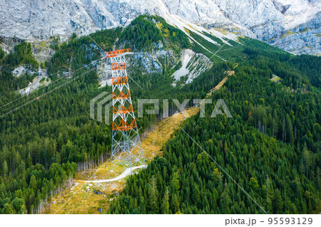 Power line pylon high in the mountains surrounded by trees, aerial view. delivery of electricity to hard to reach areas 95593129