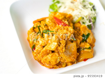 Stir-fried crab meat with curry powder, egg on a white plate, and a side dish with fresh vegetables. Popular healthy Thai seafood menu, Stir-fried crab meat with curry powder. 95593419