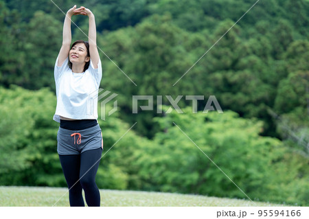 新緑の中でストレッチをする若い女性 新緑の中でストレッチをする若い女性 95594166