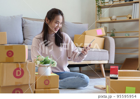 Portrait of Starting small businesses, Asian woman check online orders Selling products working with boxs freelance work at home office, sme business concepts 95595954