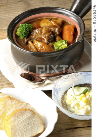 お鍋にブロッコリーや人参、しめじなど沢山の具材が入っているビーフシチューとサラダとパン お鍋にブロッコリーや人参、しめじなど沢山の具材が入っているビーフシチューとサラダとパン 95596346