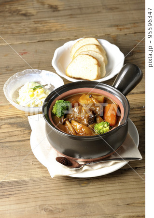 お鍋にブロッコリーや人参、しめじなど沢山の具材が入っているビーフシチューとサラダとパン お鍋にブロッコリーや人参、しめじなど沢山の具材が入っているビーフシチューとサラダとパン 95596347