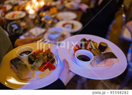 Two meat plate with salad leaves and summer salad in waiter's hand. Two meat plate with salad leaves and summer salad in waiter's hand. 95598282