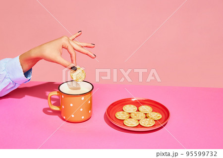 Goodies. Food pop art photography. Young girl tasting milk with crackers isolated over pink background. Concept of food, creativity. 95599732