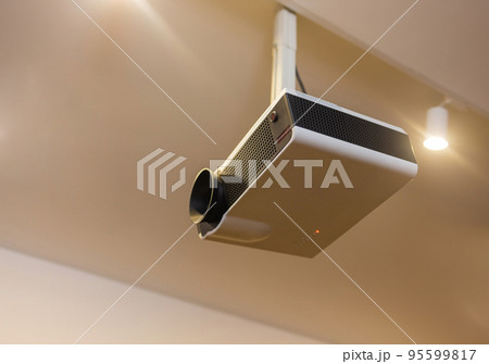 A white overhead projector on ceiling indoors. A white overhead projector on ceiling indoors. 95599817