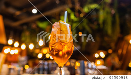 Aperol spritz cocktail in glass on wooden table on dark background in cafe. Aperol spritz cocktail in glass on wooden table on dark background in cafe. 95599918