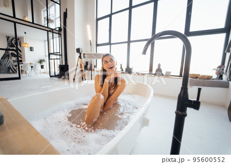 Young woman lying in foamy bath relaxes at home 95600552