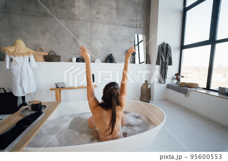 Pretty young woman taking bath at home back view Pretty young woman taking bath at home back view 95600553