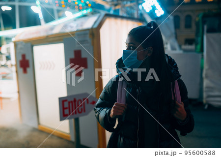 Woman in a medic mask is staying at disinfection tunnel Woman in a medic mask is staying at disinfection tunnel 95600588