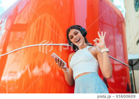 Young woman listening music with wireless headphones in the street 95600609