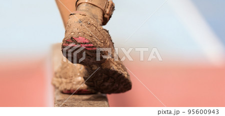Mud race runners. Participant walking on the obstacle, catches balance Mud race runners. Participant walking on the obstacle, catches balance 95600943