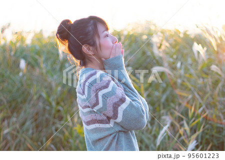 夕方にススキ畑に立っているセーターを着た女性のポートレート 95601223