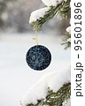 Hanging blue glitter Christmas ball on spruce and over blurred background 95601896