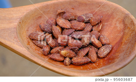 Caramelized almonds with garlic flavor in a wooden spoon 95603687