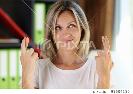 Cute smiling woman showing fingers crossed gesture 95604159